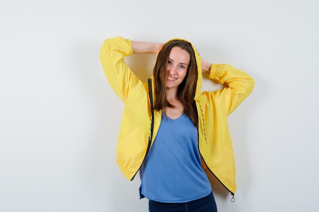 Señorita cogidos de la mano detrás de la cabeza en camiseta, chaqueta y aspecto encantador