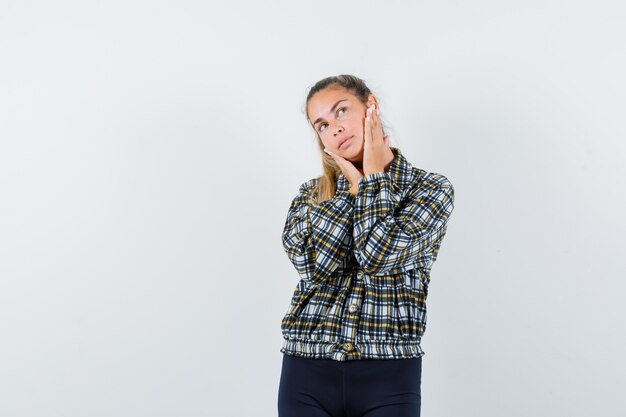 Señorita cogidos de la mano en las mejillas en camisa, pantalones cortos y con aspecto de ensueño. vista frontal.