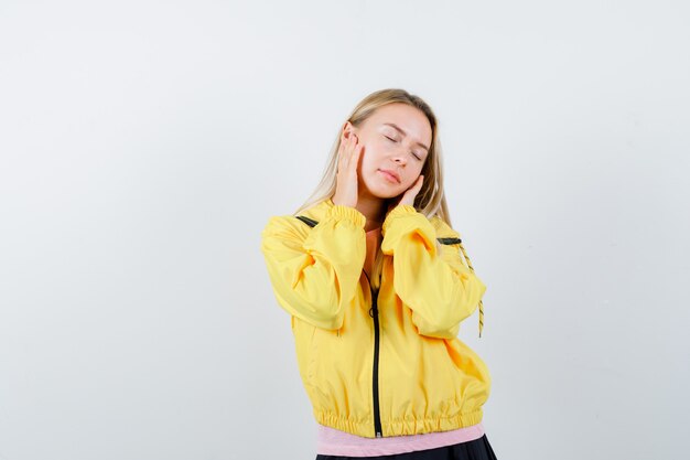 Señorita cogidos de la mano en las mejillas en camiseta, chaqueta y con sueño