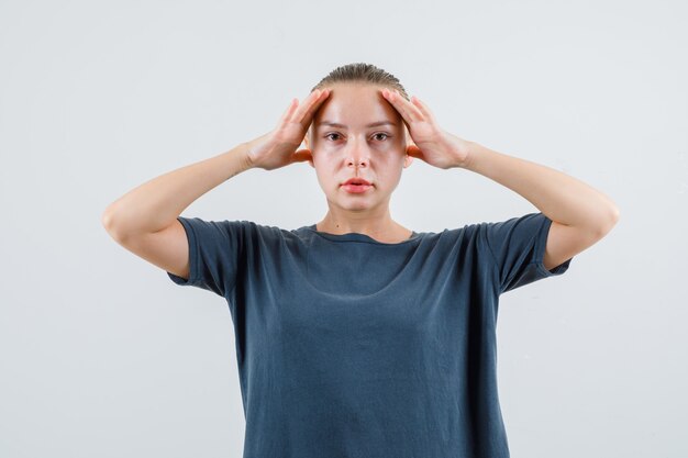 Señorita cogidos de la mano sobre la cabeza en camiseta gris y mirando con cuidado