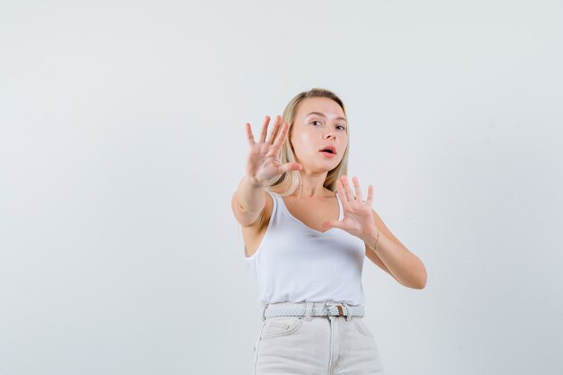 Señorita defendiéndose de algo en blusa blanca y mirando ansiosa. . espacio para texto