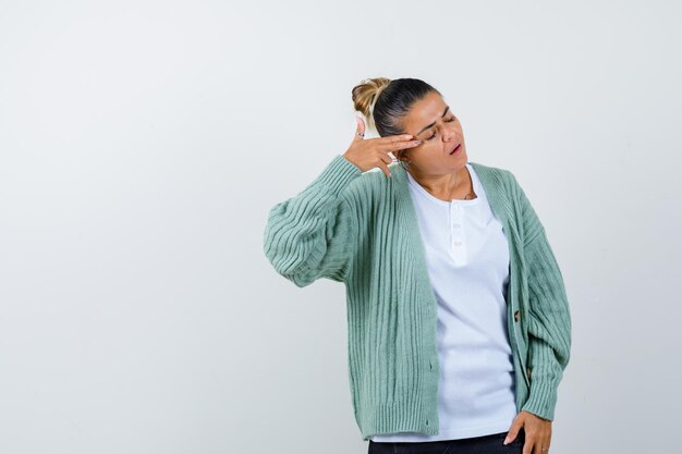 Señorita disparándose a sí misma con pistola de mano en camiseta, chaqueta y mirando desesperada