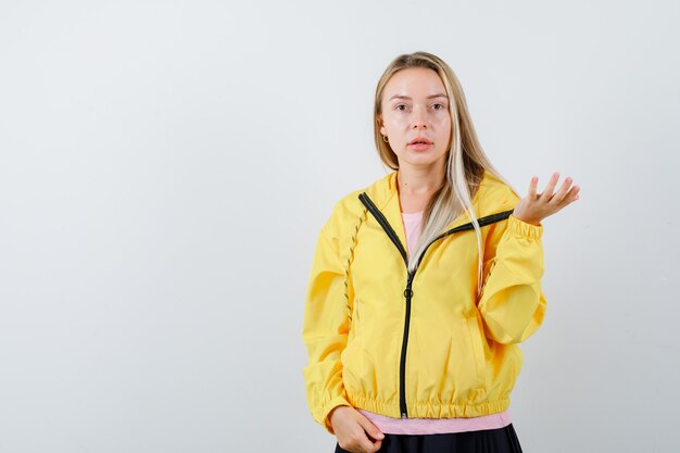 Señorita estirando la mano en gesto de interrogación en camiseta, chaqueta y mirando confiado