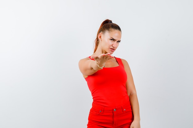 Foto gratuita señorita estirando las manos hacia la cámara en camiseta roja, pantalón rojo y mirando con cuidado, vista frontal.