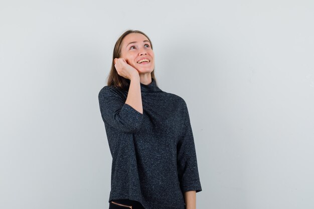 Señorita fingiendo hablar por teléfono móvil en camisa casual y mirando alegre