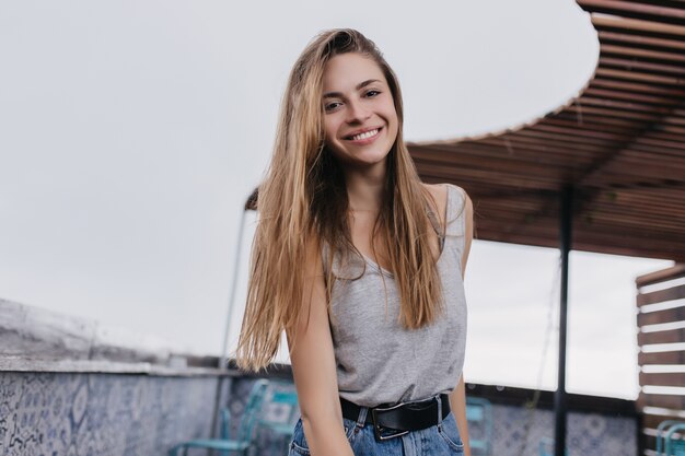 Señorita guapa con cabello claro sonriendo. Impresionante mujer joven en ropa de moda