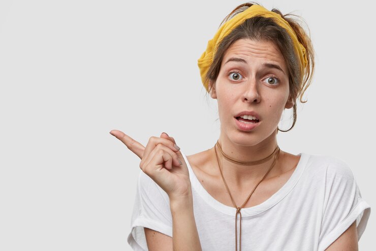 Foto gratuito la señorita insatisfecha tiene los ojos llenos de decepción, señala a un lado con el dedo índice, muestra espacio libre para su anuncio