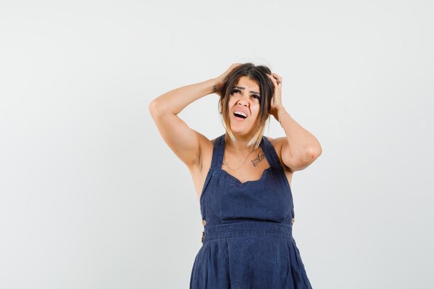 Señorita juntando la cabeza con las manos en el vestido y mirando confundido