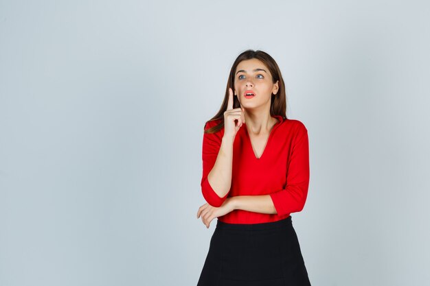 Señorita levantando el dedo índice en gesto eureka en blusa roja