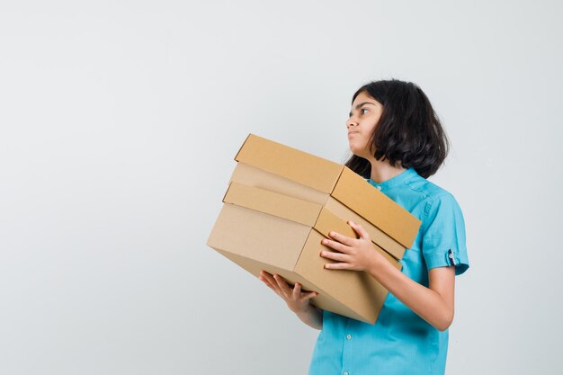 Señorita llevando cajas en camisa azul.