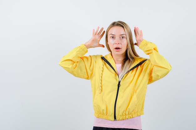 Señorita manteniendo las manos de manera agresiva en camiseta, chaqueta y mirando molesto