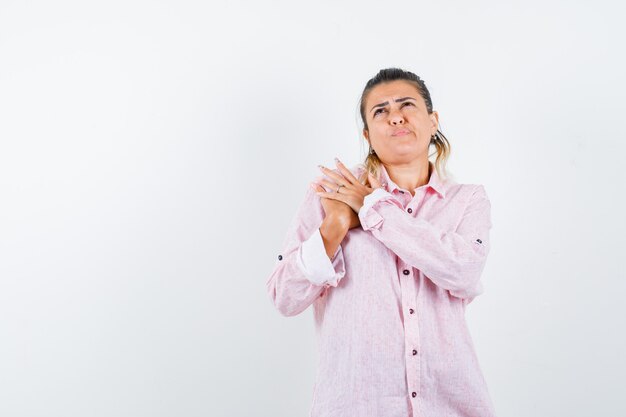 Foto gratuita señorita manteniendo las manos en el pecho con camisa rosa y mirando vacilante