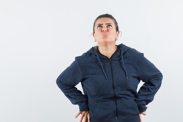 Señorita mirando hacia arriba mientras hace pucheros con los labios en la chaqueta y parece desconcertado. vista frontal.