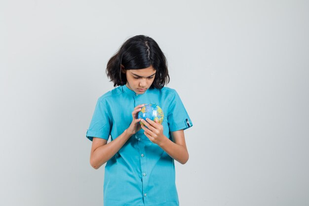 Señorita mirando mini globo en camisa azul y mirando concentrado.