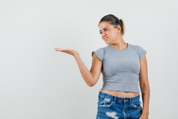 Señorita mirando su palma extendida en camiseta, pantalones cortos