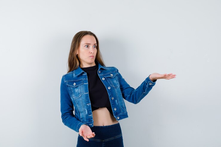 Foto gratuito señorita mostrando algo en blusa, chaqueta, jeans y mirando perplejo, vista frontal.