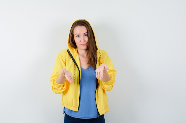 Señorita mostrando algo debajo en camiseta, chaqueta y luciendo optimista