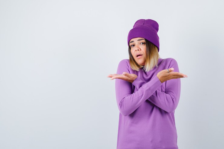Foto gratuito señorita mostrando ambos lados en suéter morado, gorro y mirando perplejo. vista frontal.