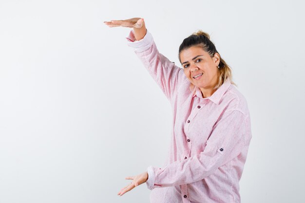 Señorita mostrando cartel de gran tamaño en camisa rosa y mirando confiado