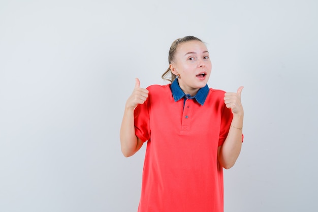 Señorita mostrando doble pulgar hacia arriba en camiseta y mirando feliz