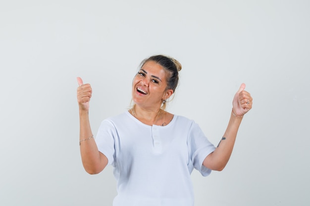 Señorita mostrando doble pulgar hacia arriba en camiseta y mirando feliz