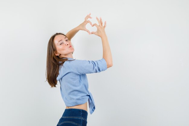 Señorita mostrando gesto de corazón, haciendo pucheros labios en camisa azul