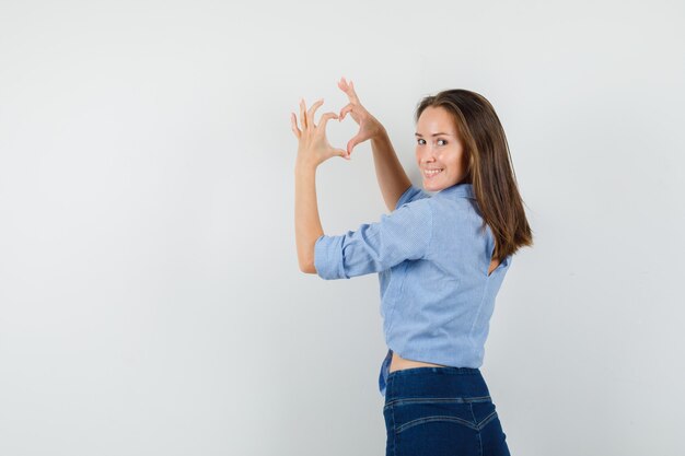 Señorita mostrando gesto de corazón y sonriendo con camisa azul
