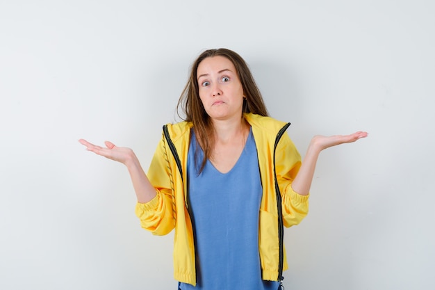 Señorita mostrando gesto de impotencia en camiseta, chaqueta y mirando confundido. vista frontal.