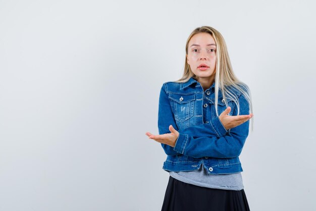 Señorita mostrando gesto de impotencia en camiseta, chaqueta vaquera, falda y aspecto atractivo