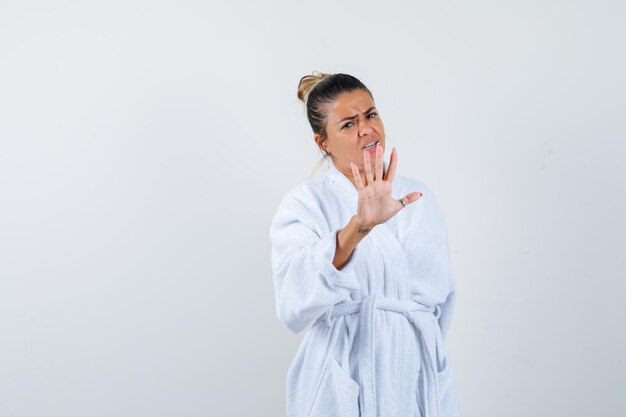 Señorita mostrando gesto de parada en bata de baño y mirando asustado