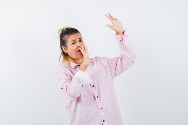 Señorita mostrando gesto de parada en camisa rosa y mirando asustado