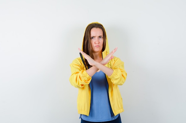 Señorita mostrando gesto de parada en camiseta, chaqueta y aspecto serio. vista frontal.