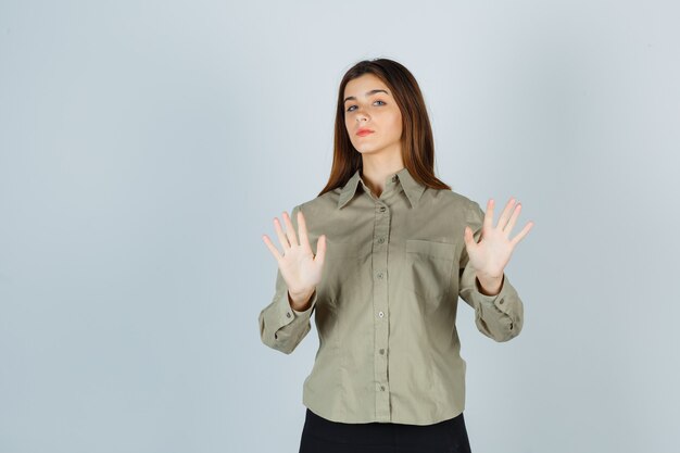 Señorita mostrando gesto de rechazo en camisa, falda y aspecto serio. vista frontal.