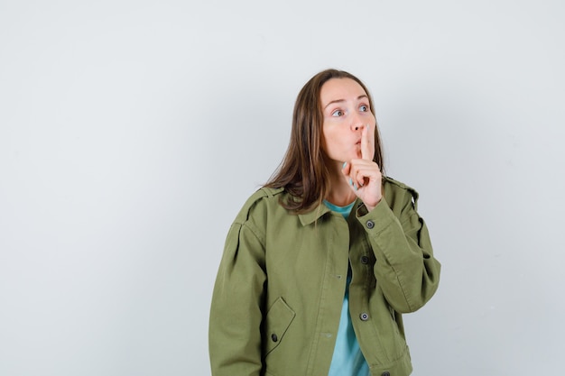 Foto gratuita señorita mostrando gesto de silencio en chaqueta verde