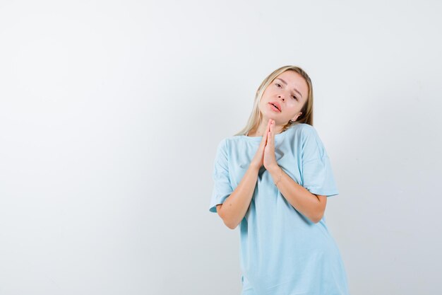 Señorita mostrando las manos juntas en gesto de súplica en camiseta aislado