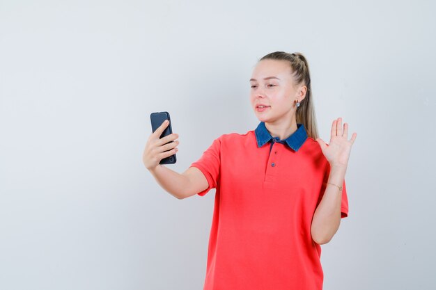 Foto gratuita señorita mostrando la palma mientras toma selfie en camiseta y se ve alegre