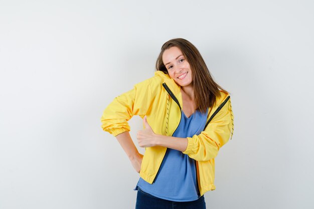 Señorita mostrando el pulgar hacia arriba encogiéndose de hombros en camiseta, chaqueta y luciendo elegante