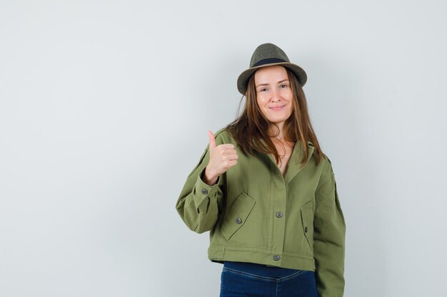 Señorita mostrando el pulgar hacia arriba en el sombrero de los pantalones de la chaqueta y mirando confiado