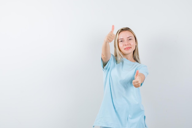 Señorita mostrando los pulgares para arriba en camiseta y mirando alegre aislado