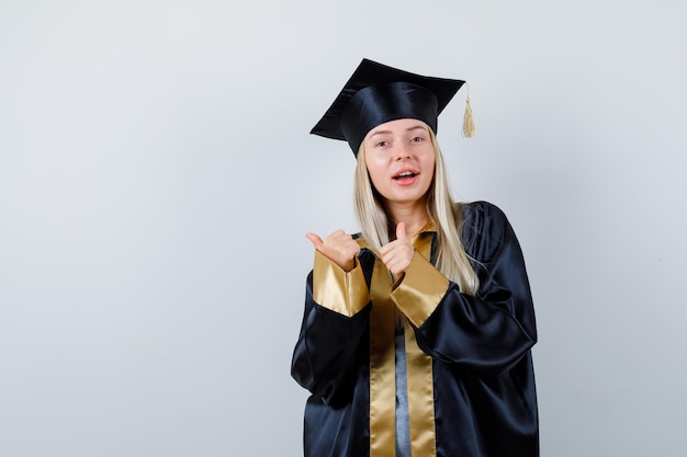 Señorita mostrando los pulgares para arriba en traje académico y mirando feliz