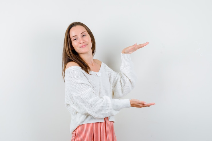 Foto gratuito señorita mostrando signo de tamaño en chaqueta de punto y falda con aspecto feliz aislado
