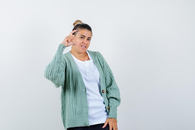 Señorita mostrando signo de tamaño pequeño en camiseta, chaqueta y mirando confiado