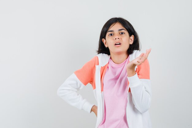 Señorita mostrando su palma abierta en chaqueta, camisa rosa y luciendo indefensa.