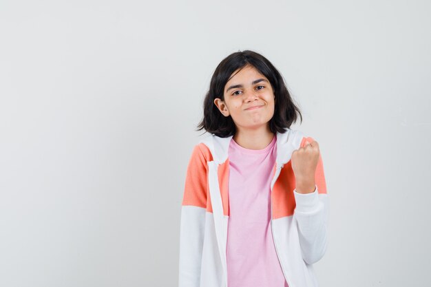 Señorita mostrando su puño en chaqueta, camisa rosa y luciendo confiada.