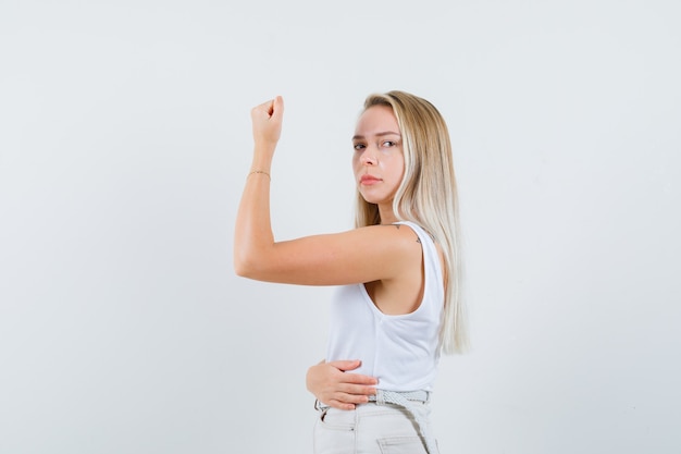 Señorita mostrando sus músculos del brazo en blusa blanca y luciendo estricta