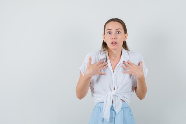 Señorita mostrándose en blusa y falda y mirando perpleja