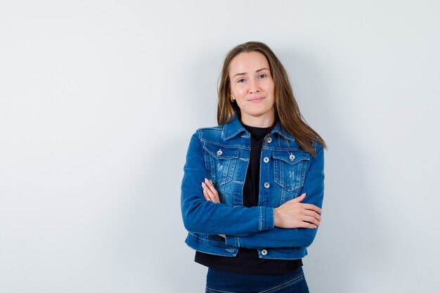 Señorita de pie con los brazos cruzados en blusa, chaqueta y mirando confiado, vista frontal.