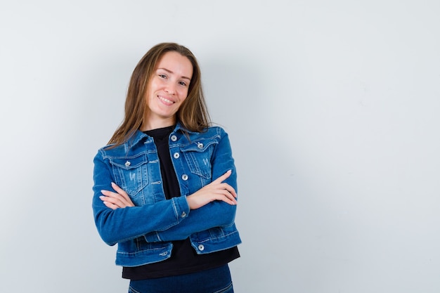 Señorita de pie con los brazos cruzados en blusa, chaqueta y mirando confiado, vista frontal.