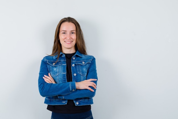 Señorita de pie con los brazos cruzados en blusa, chaqueta y mirando confiado, vista frontal.