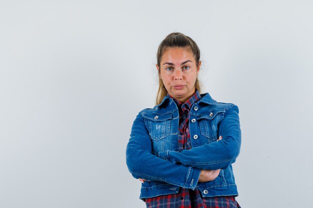 Señorita de pie con los brazos cruzados en camisa, chaqueta y mirando confiado, vista frontal.